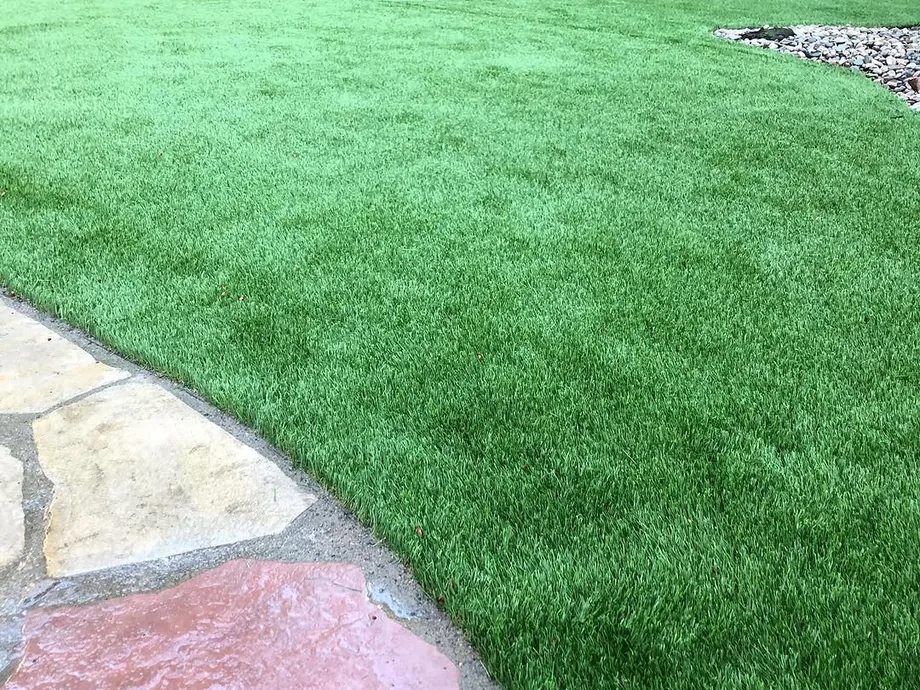 Artificial turf: synthetic turf meeting the edge of a flagstone path