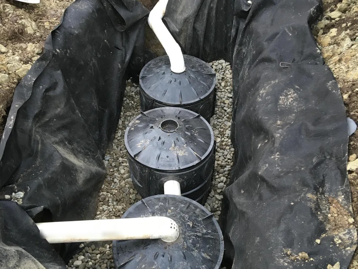 French drains and yard drainage: dry well chambers set in gravel inside a fabric-lined pit with the inlet pipe connected