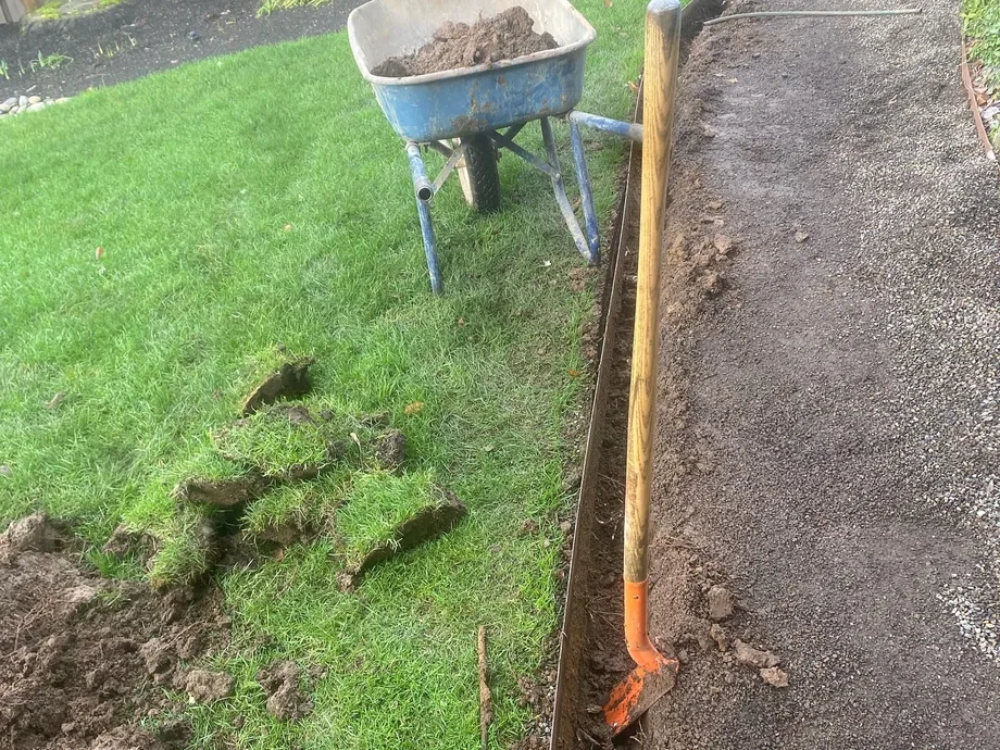 French drains: a drain line trench dug along the edge of a lawn beside a gravel path