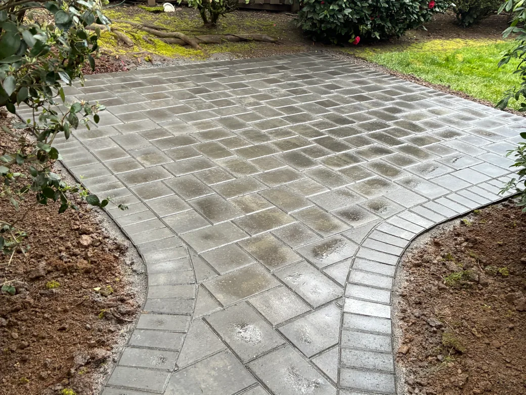 Paver patios: a curved paver walkway with a border course leading to a new paver patio between planting beds