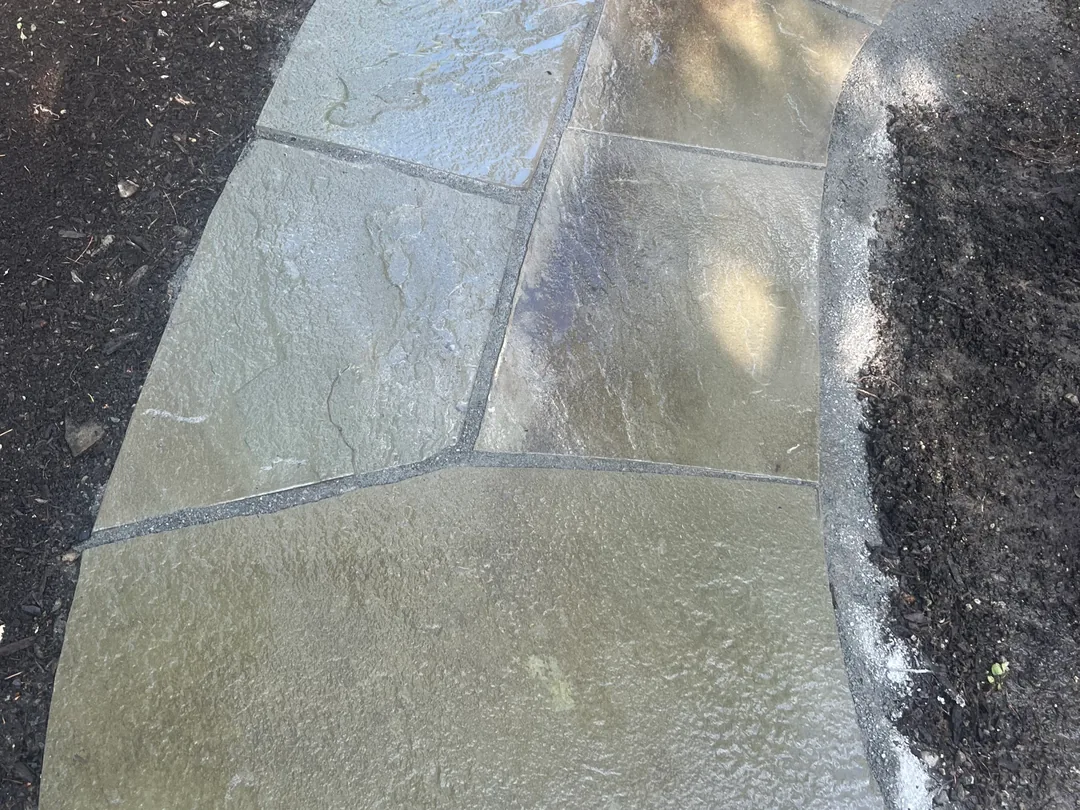 Paver patios and paths: a flagstone path set in dark soil beside a planting bed