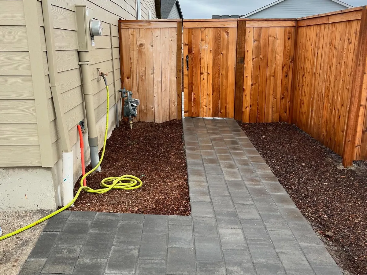 Paver patios and walkways: a new paver path through fresh bark to a cedar side gate