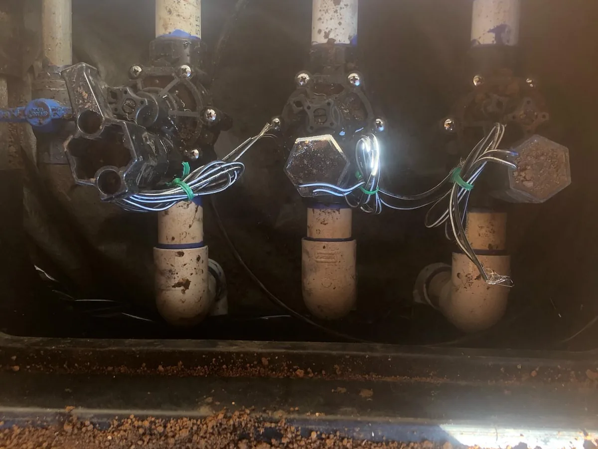 Sprinkler systems: a manifold of automatic zone valves with control wires in a valve box