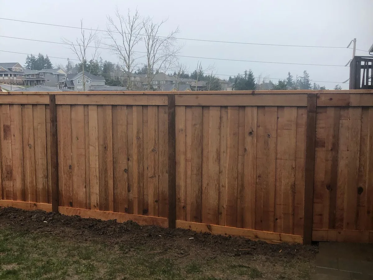 Wood fences: a new cedar privacy fence with a top cap along a lawn