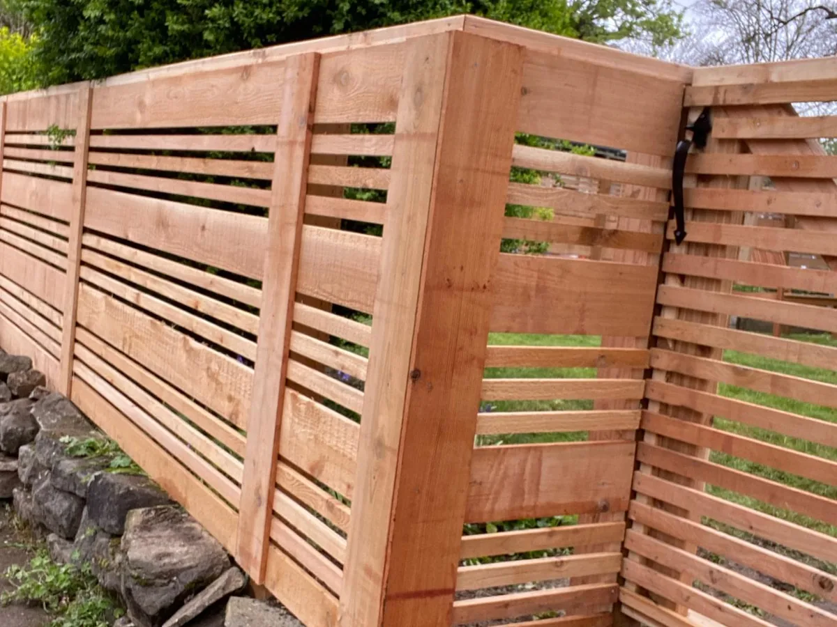 Wood fences: a new horizontal slat cedar fence on a stacked rock wall