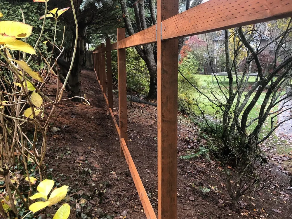 Wood fences: new cedar posts and rails set along a wooded side yard before the boards go on